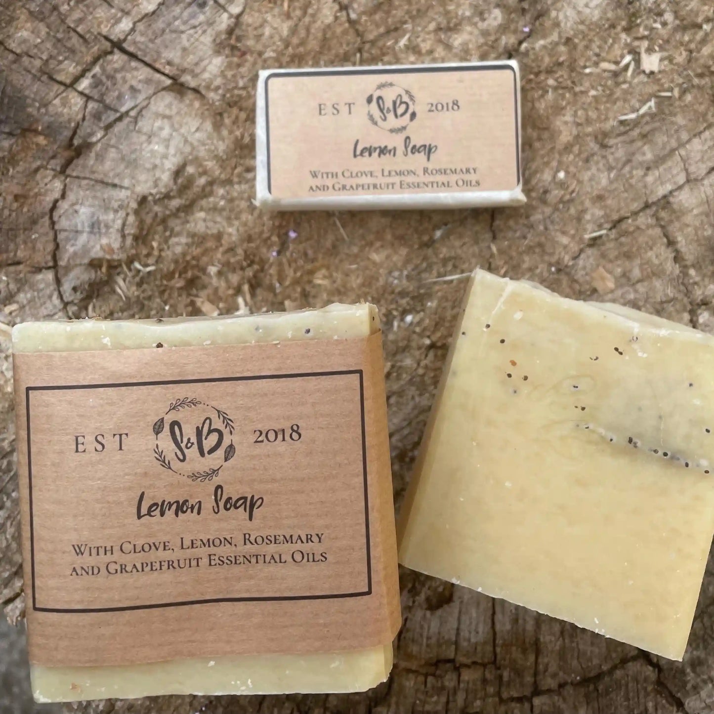 Natural lemon soap bar with and without its paper sleeve, sitting on a rustic wooden background.
